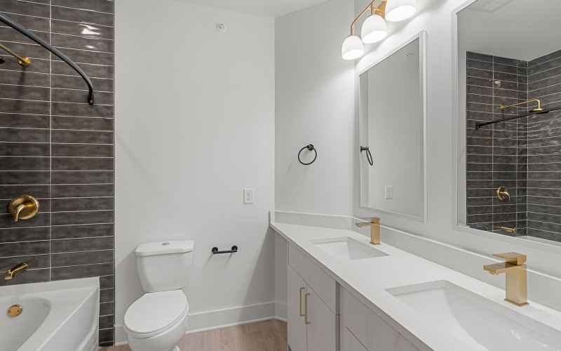 Brushed brass sink faucets and satin brass pulls add a refined touch to the bathroom design.